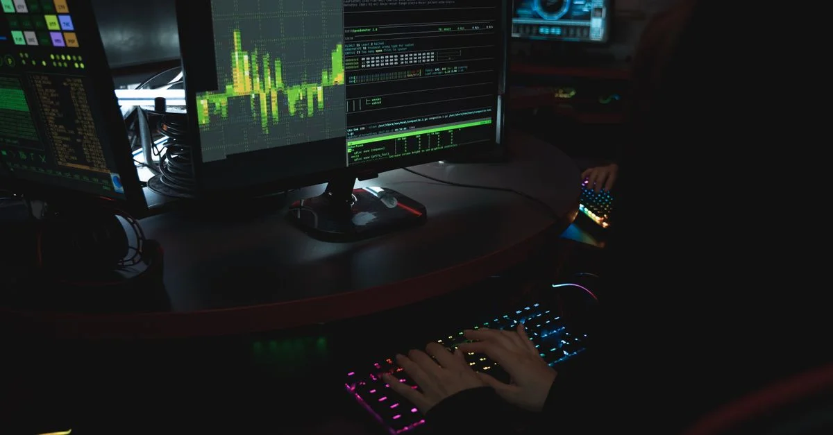 Un expert en cybersécurité dans une pièce faiblement éclairée tape sur un clavier coloré avec plusieurs écrans affichant des données.