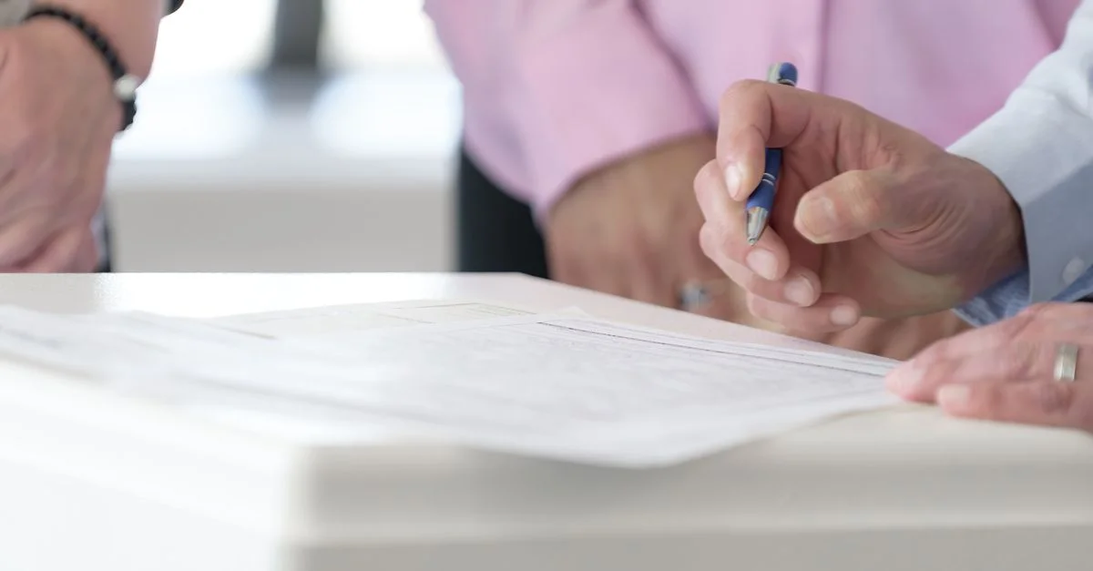 Gros plan sur des mains signant des documents dans un environnement de bureau, mettant en avant la collaboration et la prise de décision.