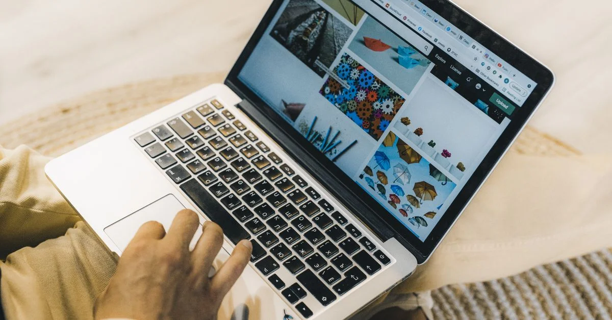 Une personne utilisant un ordinateur portable pour parcourir des sites de photos de stock. Travail en freelance dans un cadre confortable.