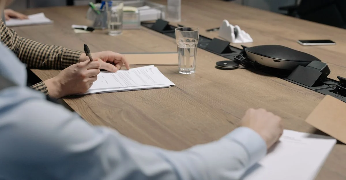 Cadre professionnel d'une réunion d'affaires avec des individus signant des documents sur une table de conférence.