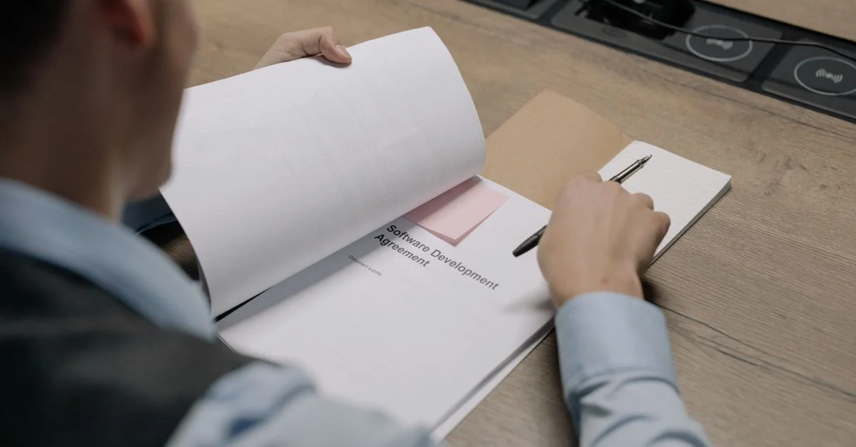 Professionnel d'affaires au bureau examinant un document d'accord de développement logiciel.