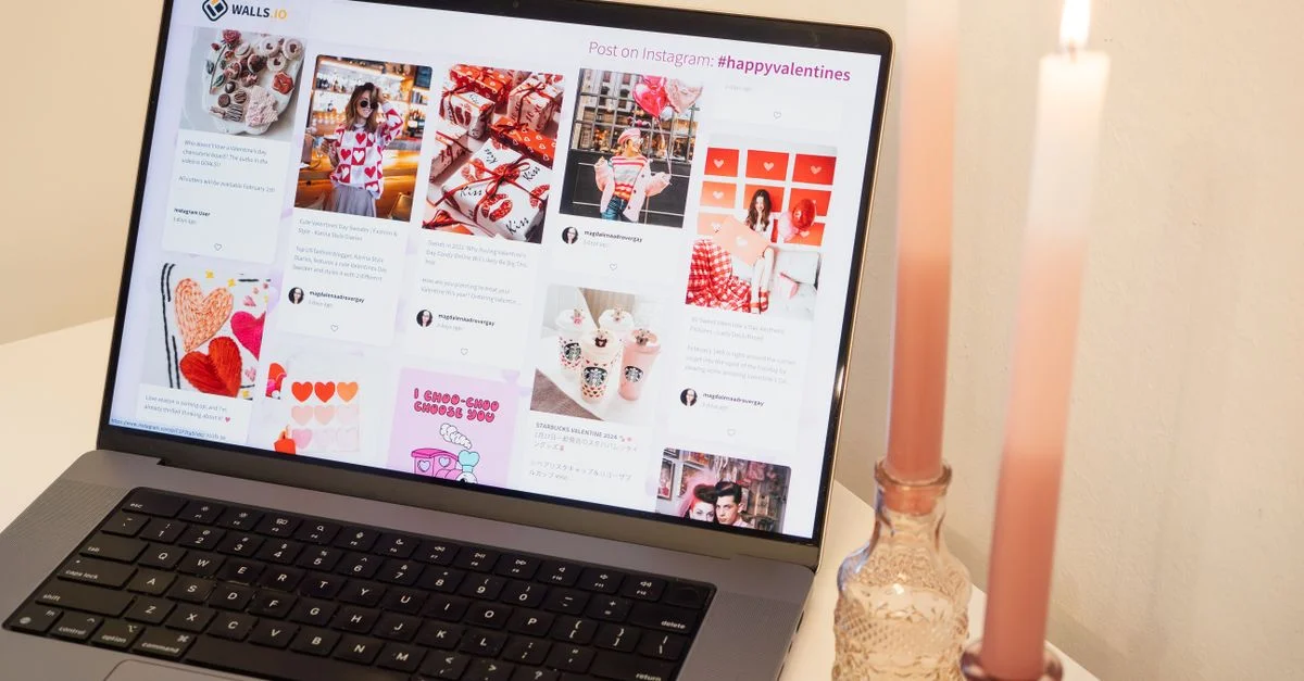 Un décor romantique avec un ordinateur portable affichant des publications sur la Saint-Valentin et des bougies roses, parfait pour une ambiance chaleureuse.