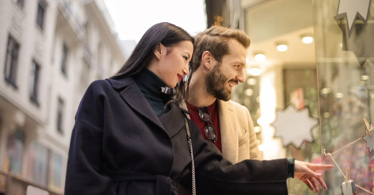 Femme asiatique et homme en train de faire du lèche-vitrine dans une rue urbaine animée pendant la journée.