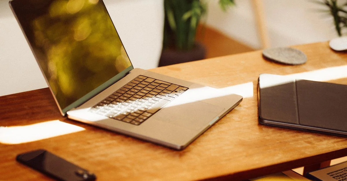 Un coin bureau confortable à domicile avec un ordinateur portable, un smartphone et une tablette sur un bureau en bois à l'intérieur.