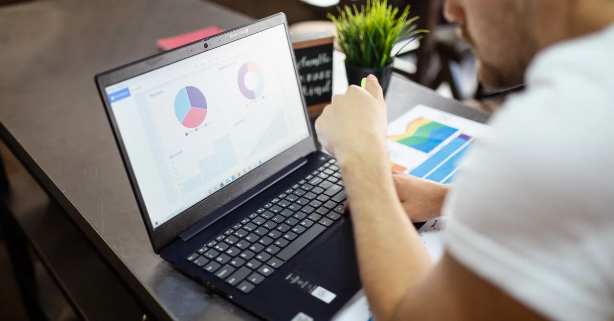 Homme examinant des graphiques et des tableaux sur un ordinateur portable pour une analyse commerciale.
