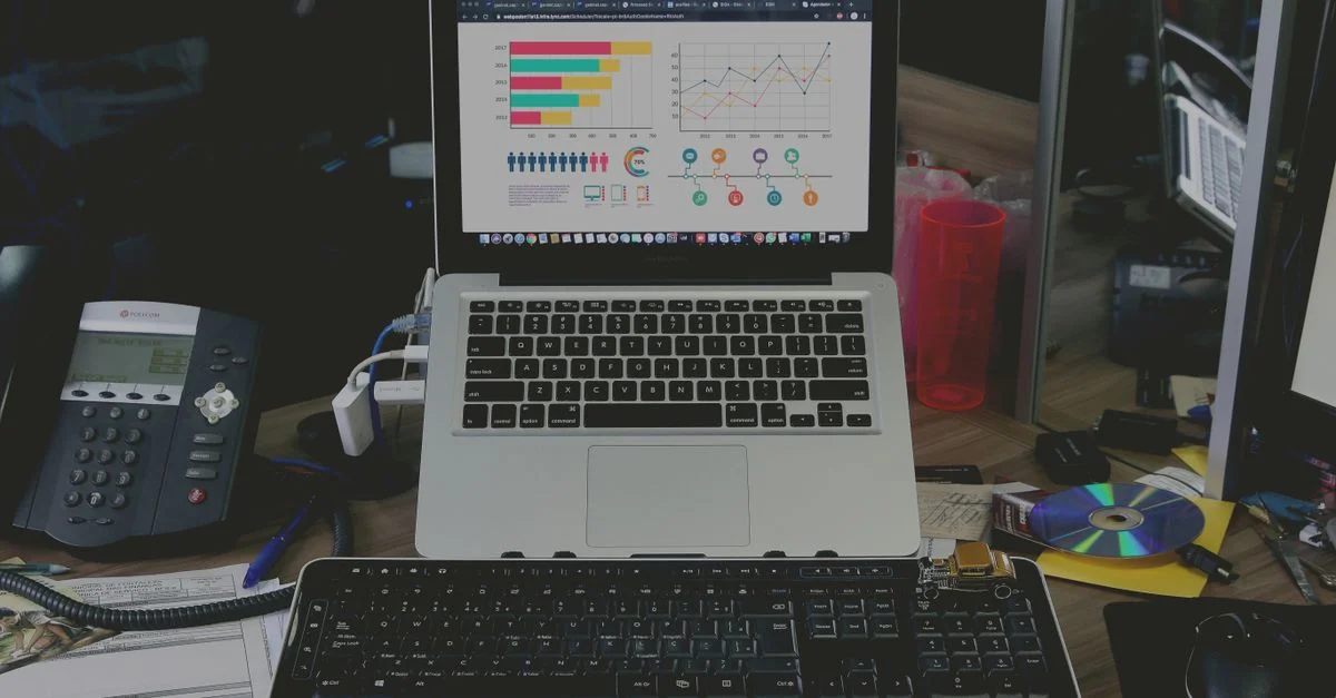 Un espace de travail soigné avec un ordinateur portable affichant des graphiques de données colorés, illustrant un environnement technologique.